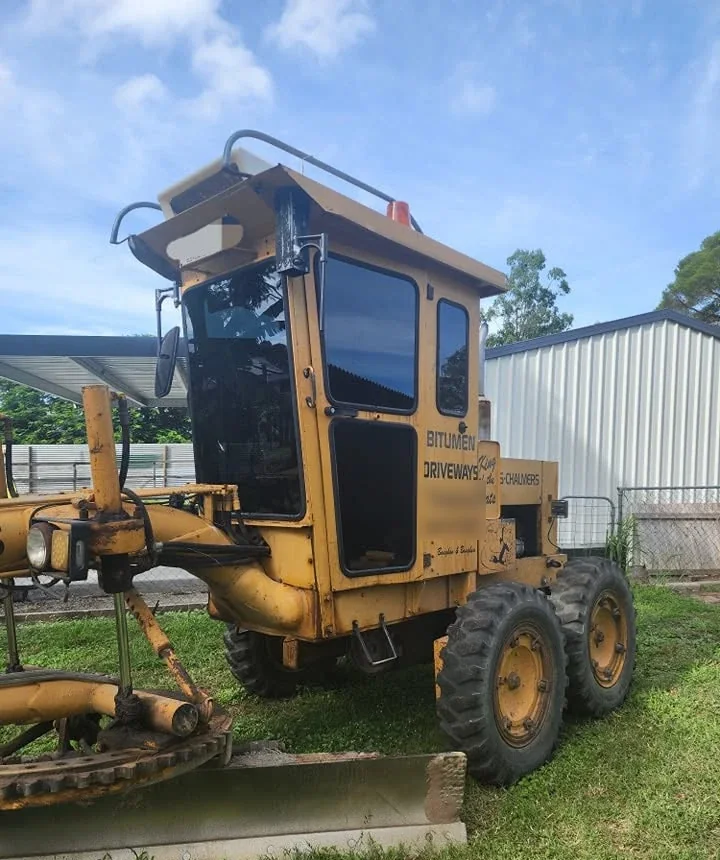 Yellow road grader with a tinted cab